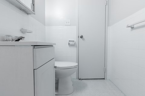 A white bathroom with a toilet, sink, and shower.
