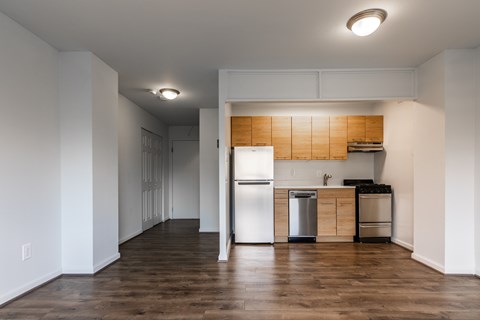 A kitchen with a refrigerator, stove, and trash can.