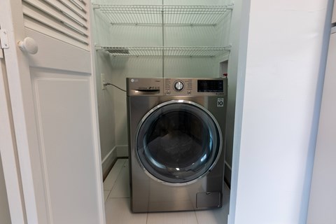 A washing machine is sitting in a small, white-walled laundry room.