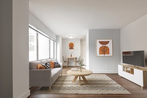 A living room with a grey couch, a wooden coffee table, and a painting on the wall.