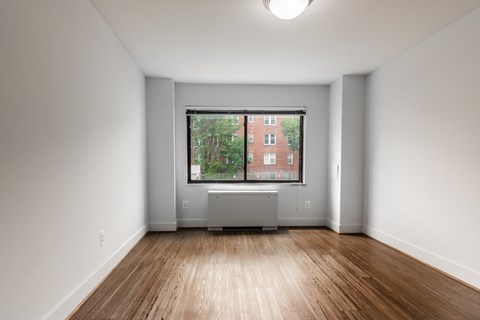 A room with a window overlooking a red building.