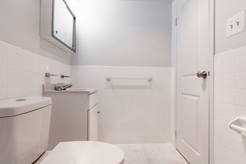 A white bathroom with a toilet, sink, and mirror.