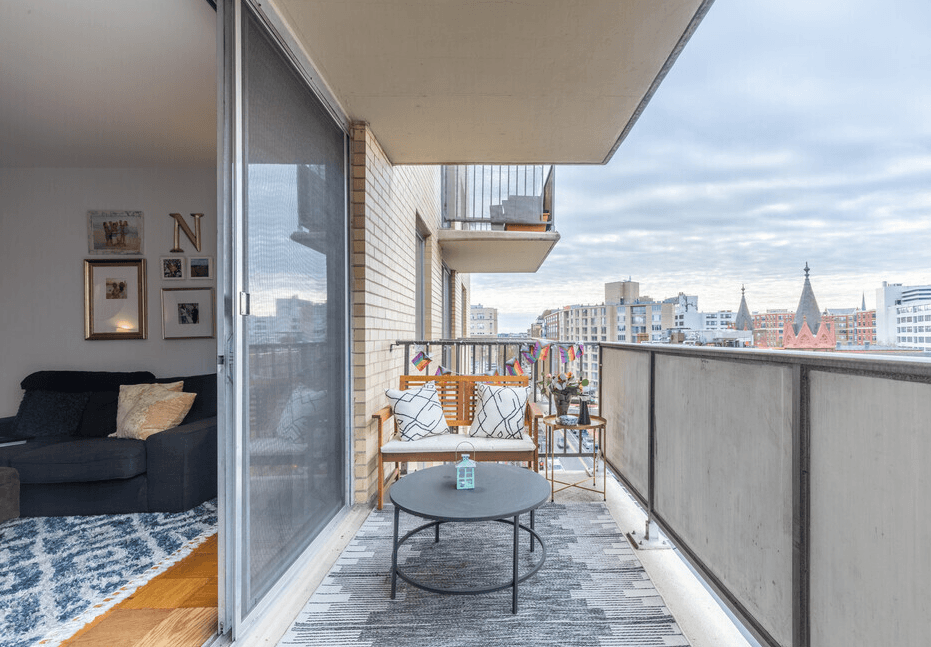 A balcony with a table and chairs overlooking a cityscape.