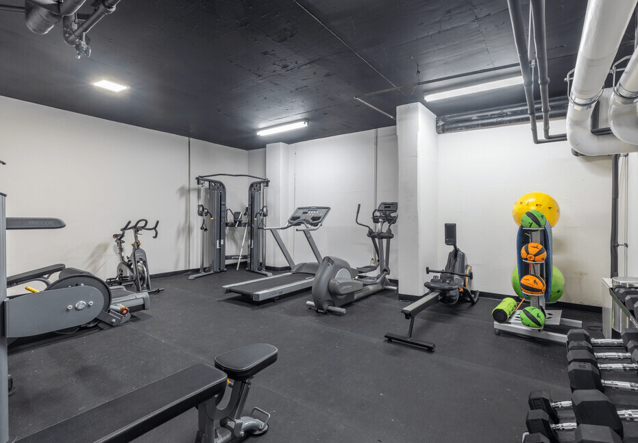 A gym with a variety of equipment including treadmills, weights, and exercise machines.