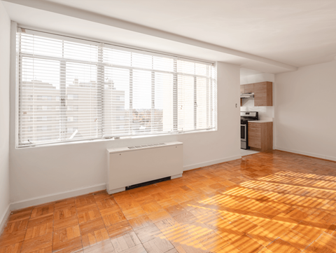 A room with a window and a radiator on the floor.