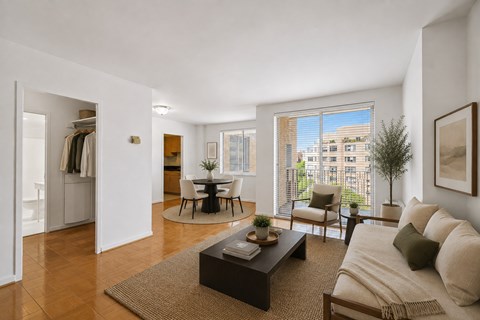 A living room with a couch, coffee table, and a view of a building outside the window.