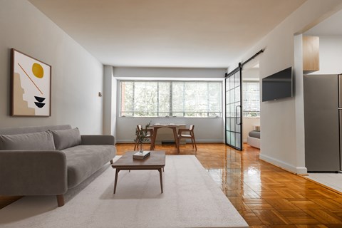 A living room with a grey couch, a coffee table, and a painting on the wall.