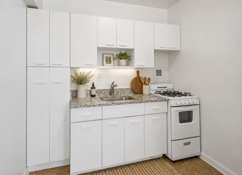 A white kitchen with a stove and sink.