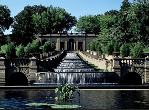 A small waterfall flows into a pond in front of a building.