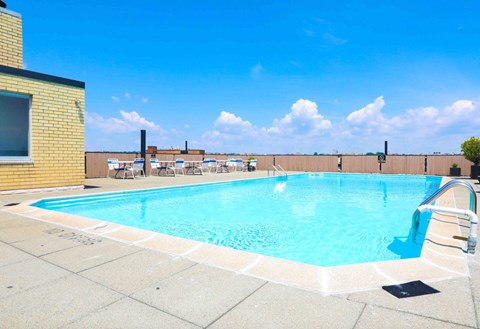 A swimming pool with a blue sky and clouds in the background.