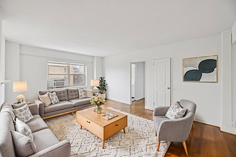 A living room with a grey couch, a coffee table, and a painting on the wall.