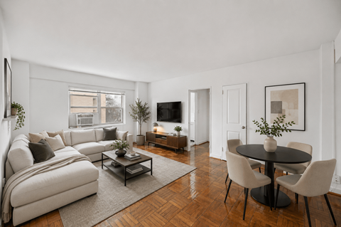 A living room with a white couch, a coffee table, and a TV.