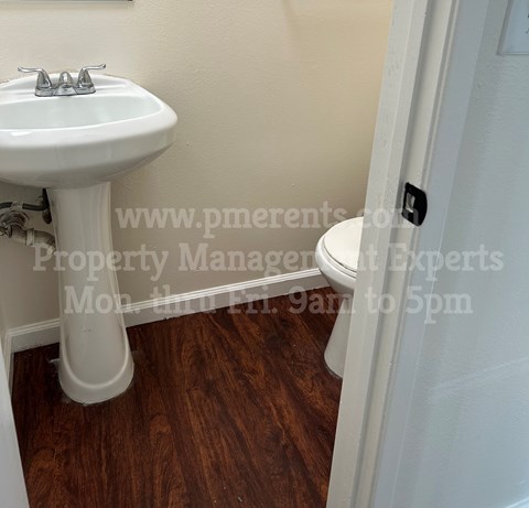 A white sink is in a small bathroom with wood floors.