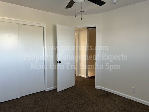 A room with a ceiling fan and a door leading to another room.