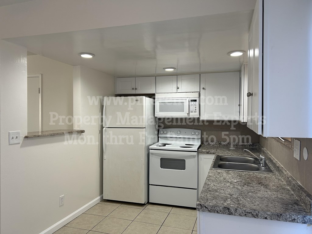 A kitchen with white appliances and a granite countertop.