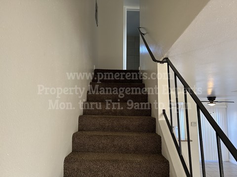A staircase with a carpeted runner and a metal railing.