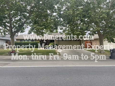 A tree-lined street with a sign for www.pinerents.com Property Management Experts.