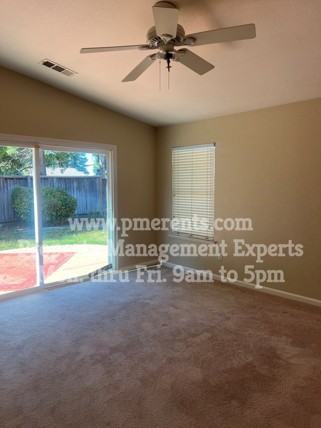 a living room with a large window and a ceiling fan