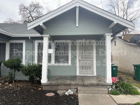 A small house with a front porch and a satellite dish on the roof.