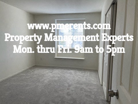 A room with a door and a sign that says www.pmoments.com Property Management Experts Mon. thru Fri. 9am to 5pm.