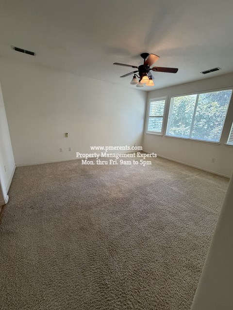 A room with a ceiling fan and a window with blinds.
