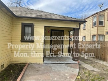 a small yellow house with a sidewalk in front of it
