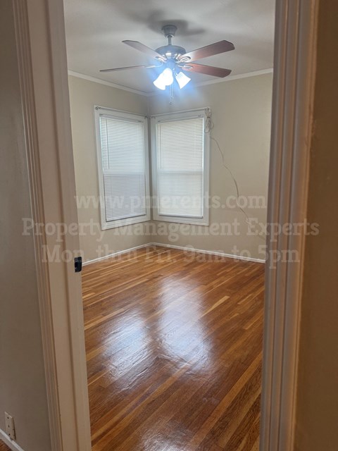 A room with a ceiling fan and wooden flooring.