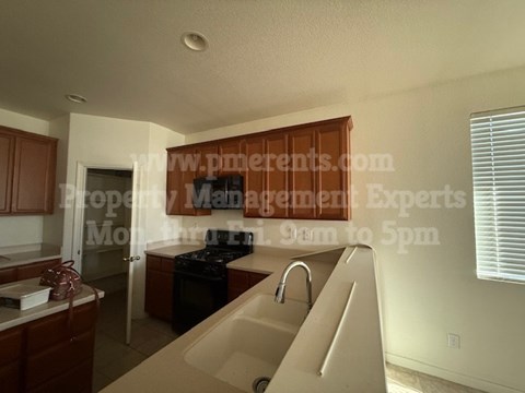A kitchen with a sink and a window with blinds.