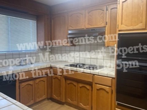 A kitchen with wooden cabinets and a black oven.