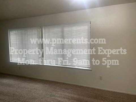 a living room with two windows and a carpet