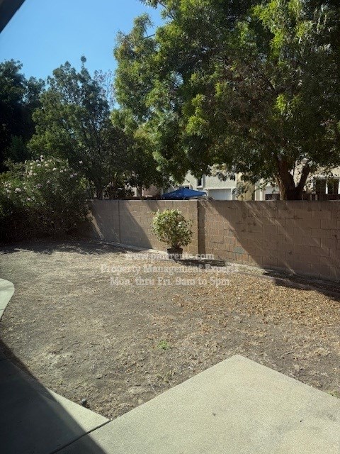 A backyard with a concrete patio and a wall.