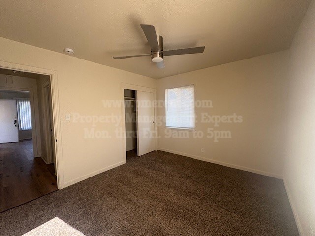 A room with a carpeted floor and a ceiling fan.