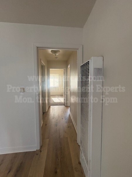 A long hallway with a white wall and a window.