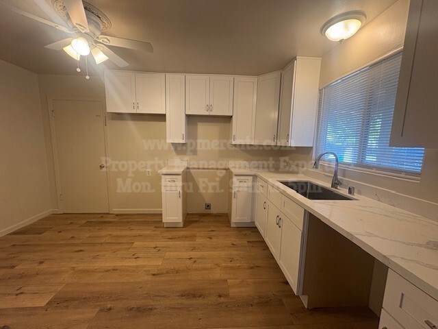 A kitchen with wooden floors and white cabinets.