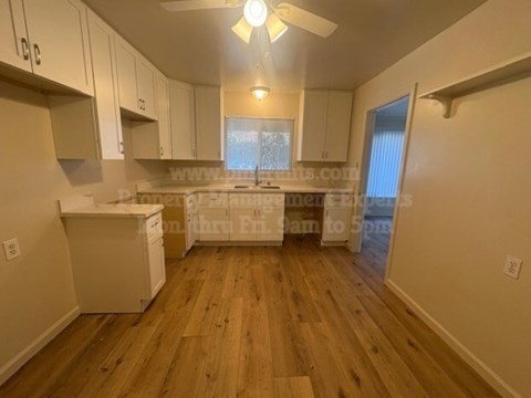 A kitchen with white cabinets and a wooden floor.