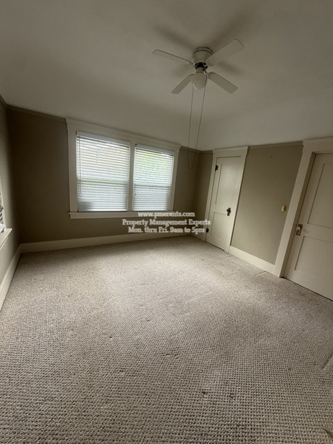 A room with a ceiling fan and carpeted floor.