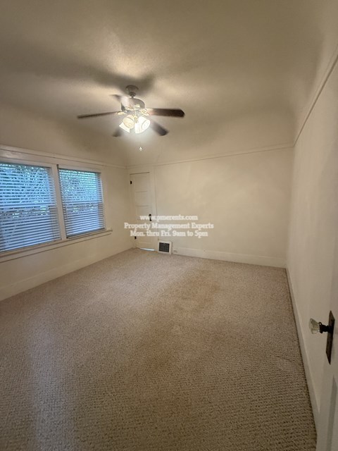 A room with a ceiling fan and carpeted floor.
