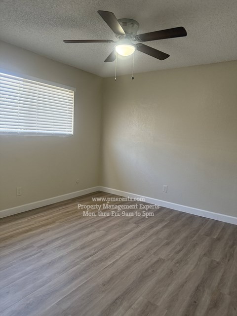 A room with a ceiling fan and a window with blinds.