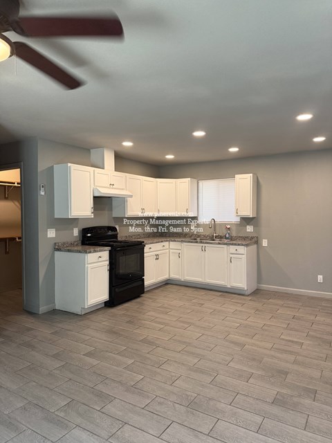 A kitchen with white cabinets and a black stove top oven.