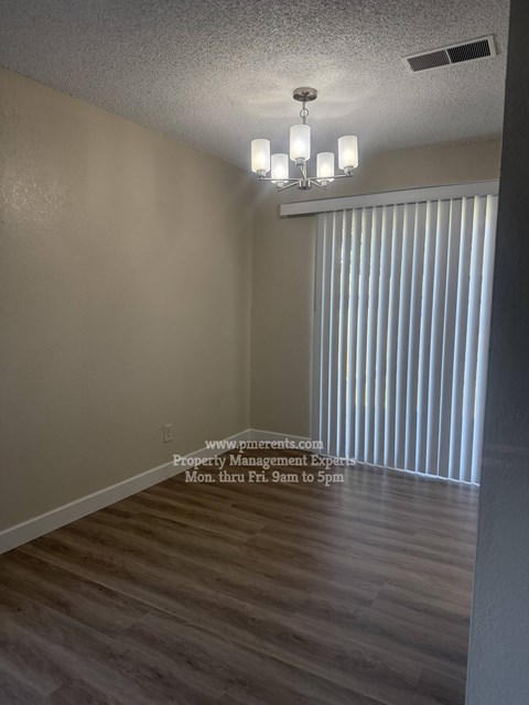 A room with a chandelier and a sign that says "www.p-parents.com Property Management Experts Mon. thru Fri. 9am to 5pm".