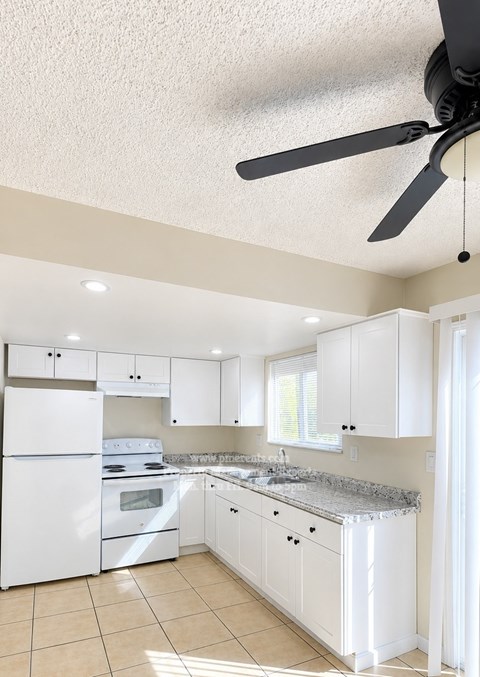 A white kitchen with a fan on the ceiling.