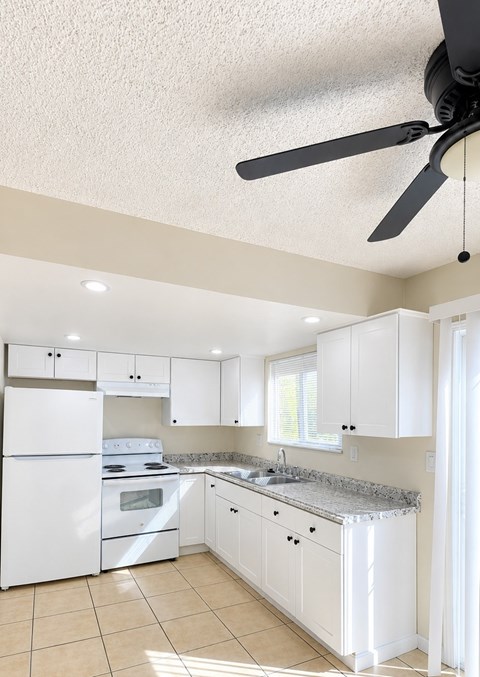 A white kitchen with a fan on the ceiling.