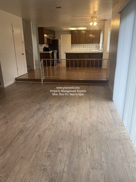 A spacious room with wooden flooring and a balcony with a railing.