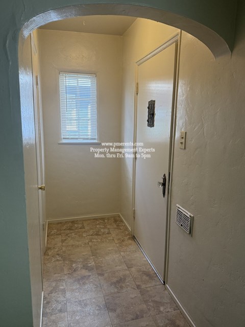 A hallway with a door on the right and a window on the left.
