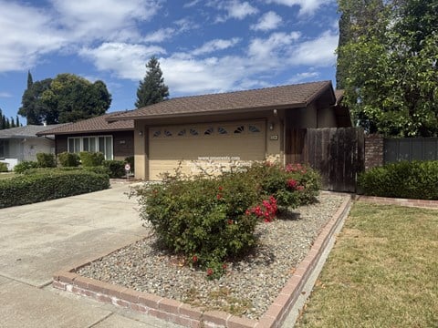 A house with a brown roof and a garden in front.