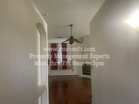 a hallway leading to a living room with a ceiling fan