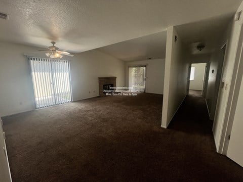 A spacious room with carpeted floor and a ceiling fan.