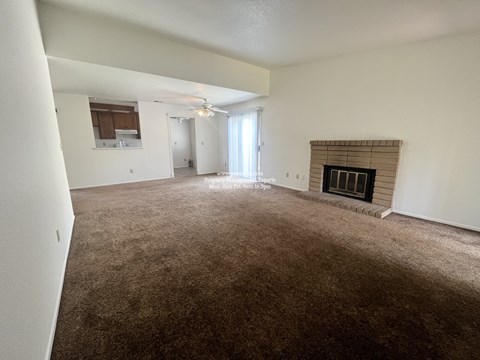 A living room with a fireplace and carpeted floor.