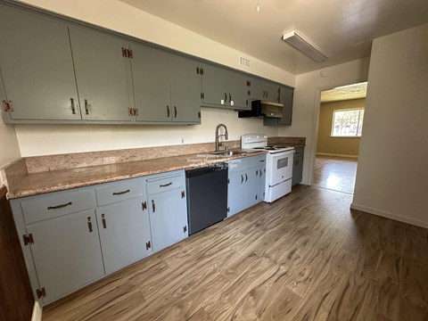 A kitchen with white cabinets and a wooden floor.