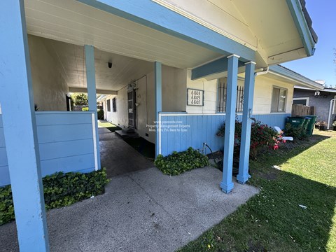 A blue house with a sign that says "For Sale" on the front porch.